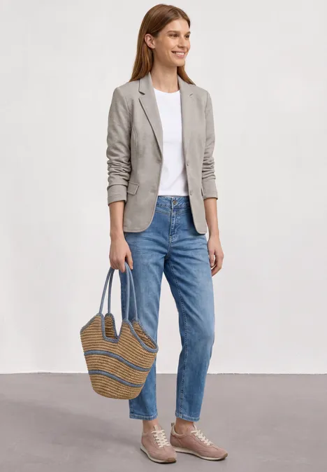Basic Piqué Blazer clay sand Frau trägt Jeans, weißes T-Shirt, graue Jacke und geflochtene Tasche.