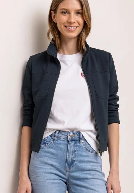 Iemand draagt een wit t-shirt, blauwe jeans en een donkerblauwe jas.