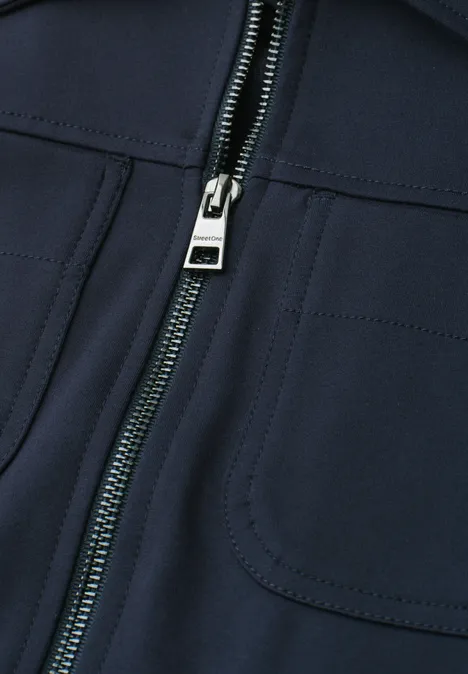 Close-up van een donkerblauwe jas met ritssluiting en borstzakken van softshell.