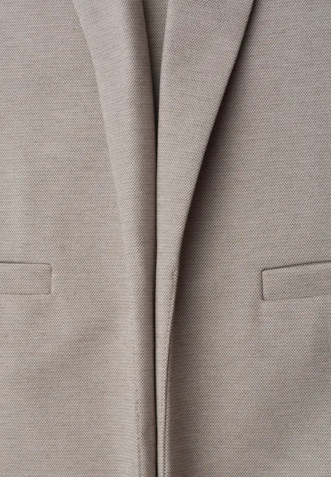 Nahaufnahme eines hellbeigen Blazers mit Taschen auf der Vorderseite