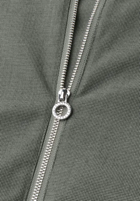 Nahaufnahme eines silbernen Reißverschlusses an olivgrünem Stoff.