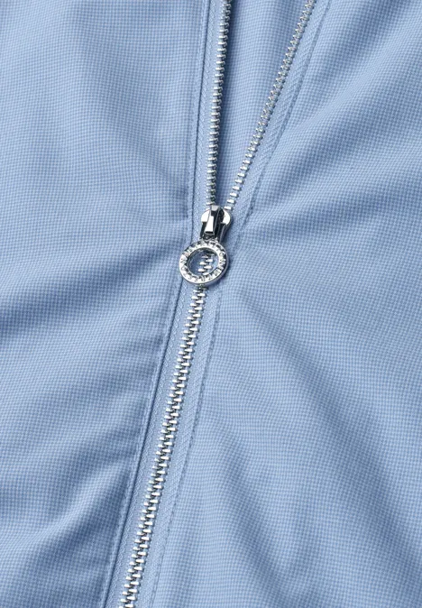 Detailaufnahme eines silbernen Reißverschlusses auf hellblauem Stoff