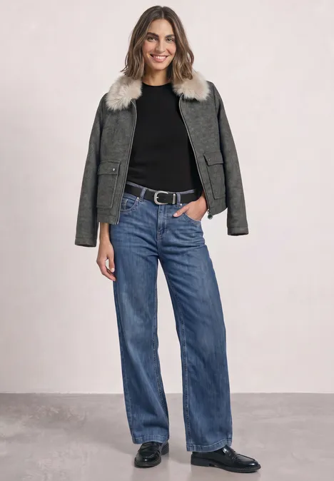 Overshirt mit Woll-Anteil und Fake-Fur-Kragen Obsidian Blue Frau in schwarzem Shirt, grüner Jacke mit Fellbesatz, weiter Jeans und schwarzen Schuhen.