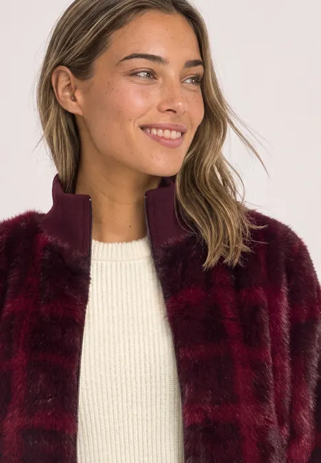 Fake Fur Blouson mit Strickdetails und Print plummy brown Eine lächelnde Frau mit weinroter Kunstfelljacke und weißem Pullover, Blick zur Seite.