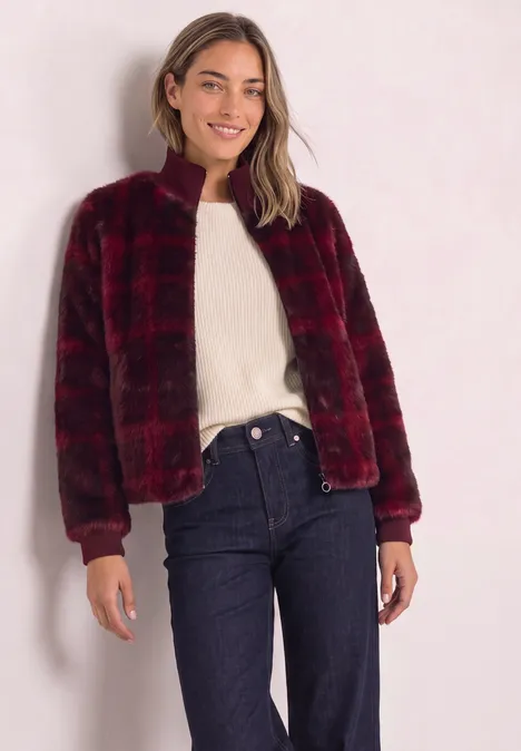 Fake Fur Blouson mit Strickdetails und Print plummy brown Frau trägt rotschwarz karierte, flauschige Jacke mit Reißverschluss über weißem Pullover und Jeans.