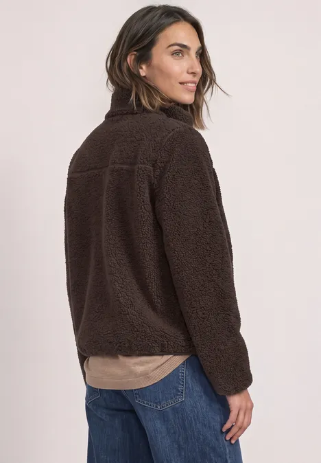 Teddy-Jacke mit Stehkragen und Zipper auburn brown Frau trägt kuschelige braune Fleece-Jacke, seitlich abgewandt, mild lächelnd.