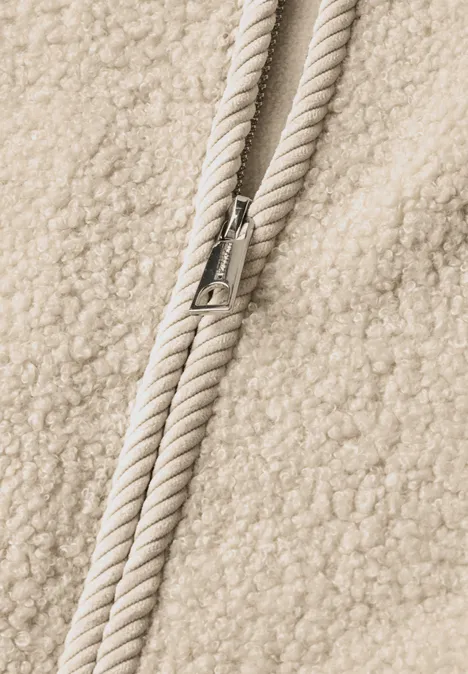 Veste en peluche à col rond et détails en velours côtelé Soft Fawn Beige Nahaufnahme einer flauschigen Fleecejacke mit Kordelzug und Metallkordelenden.