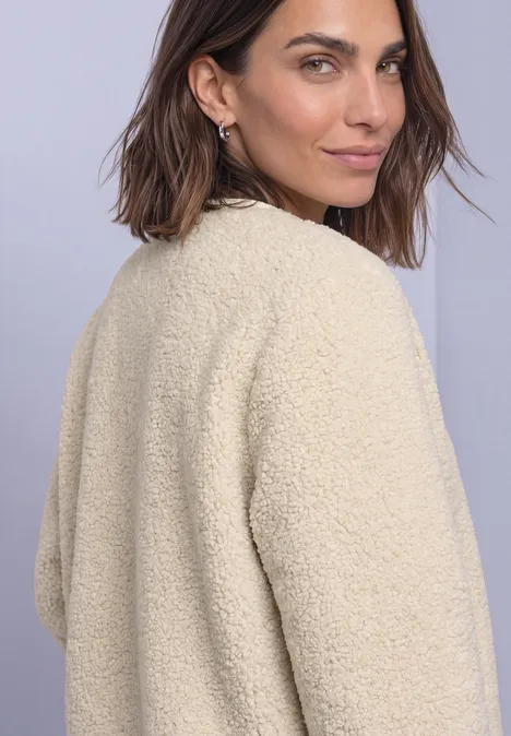Veste en peluche à col rond et détails en velours côtelé Soft Fawn Beige Eine Frau in einem beigen Teddy-Mantel blickt über die Schulter.