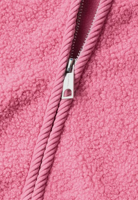 Gros plan d’une fermeture éclair rose sur un tissu Teddy polaire doux.