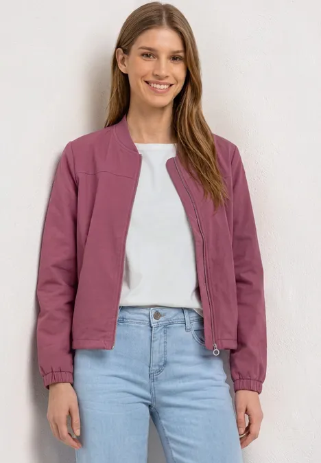 Blouson met lange mouwen en ritssluiting dark clouded blush Een vrouw draagt een paarse korte jas over een wit T-shirt en spijkerbroek, tegen een lichte achtergrond.