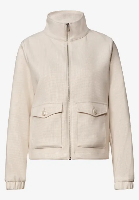 Beige Fleece-Jacke mit Stehkragen, Reißverschluss und aufgesetzten Taschen.