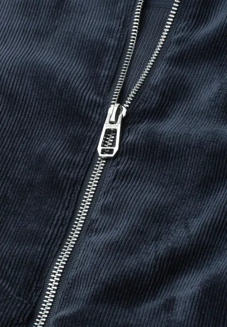 Nahaufnahme eines silbernen Reißverschlusses an dunkelblauem Cordstoff