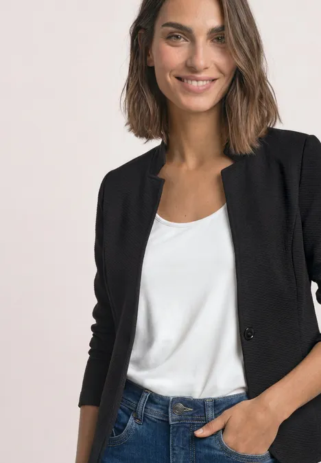 Blazer mit Reverskragen und Struktur Black Eine lächelnde Frau in schwarzem Blazer und weißem Shirt, Hand in der Hosentasche.