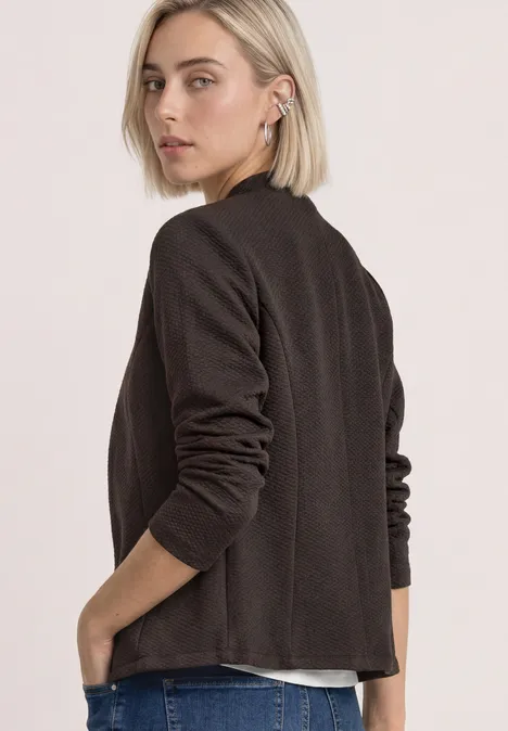 Blazer mit Reverskragen und Struktur black coffee mel. Frau mit kurzem blondem Haar trägt einen schwarzen Blazer, steht seitlich und blickt über die Schulter.