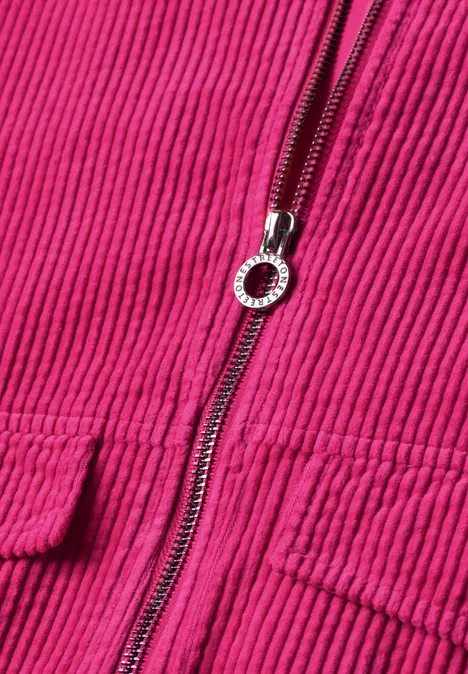 Nahaufnahme einer pinken Cordjacke mit silbernem Reißverschluss und Taschen