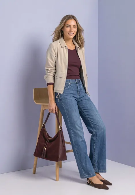 Cordjacke mit Hemdkragen und Zipper clay sand Frau trägt beigen Blazer, dunkelrotes Top und weite Jeans, hält braune Tasche vor lila Hintergrund.