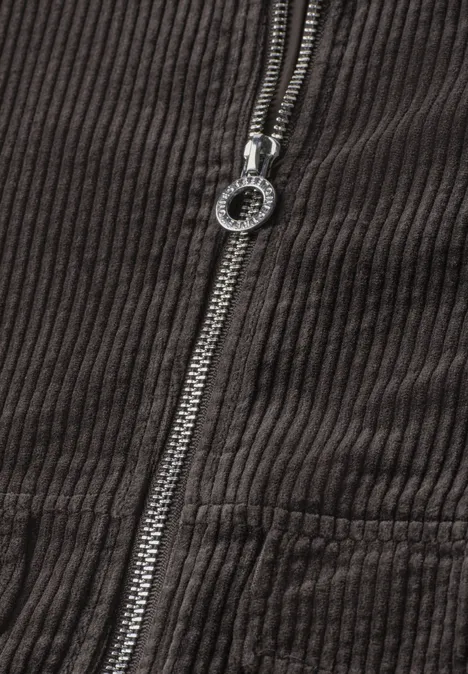 Nahaufnahme einer braunen Kordjacke mit Metallreißverschluss und rundem Zipperzug
