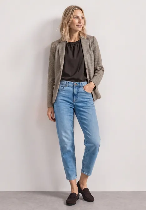 Eenvoudige blazer met reverskraag en patroon saddle brown Eine Frau mit blondem Haar trägt grauen Blazer, schwarzes Shirt, blaue Jeans und schwarze Slipper.
