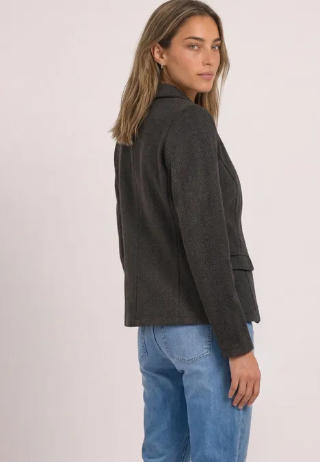 Eenvoudige blazer met reverskraag en patroon black coffee Frau steht seitlich, trägt dunkelgraues Sakko und blaue Jeans.