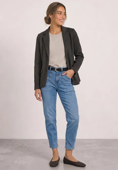 Eenvoudige blazer met reverskraag en patroon black coffee Frau in schwarzem Blazer, grauem Shirt, blauen Jeans und braunen Loafers, lächelnd seitlich stehend.