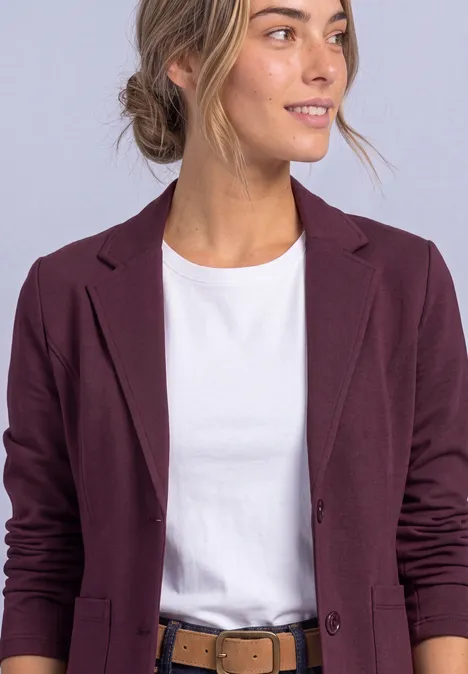 Blazer basique uni rustic rouge Frau im weißen T-Shirt und figurschmeichelndem, dunkelviolettem Blazer, Blick nach rechts.