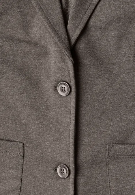 Nahaufnahme eines graubraunen Blazers mit zwei Knöpfen und seitlichen Taschen.