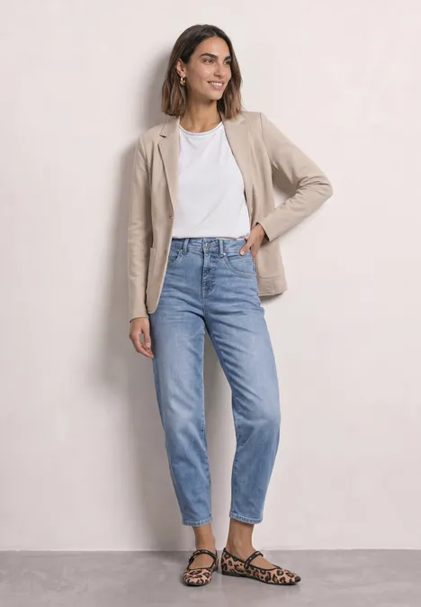 Basic Blazer in Unifarbe clay sand mel. Frau trägt beige Blazer, weißes T-Shirt, blaue Jeans und Leoparden-Sandalen vor hellem Hintergrund.