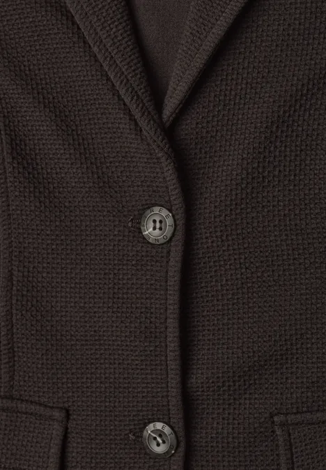 Nahansicht einer braunen Strickjacke mit zwei Knöpfen und Taschen vorne.