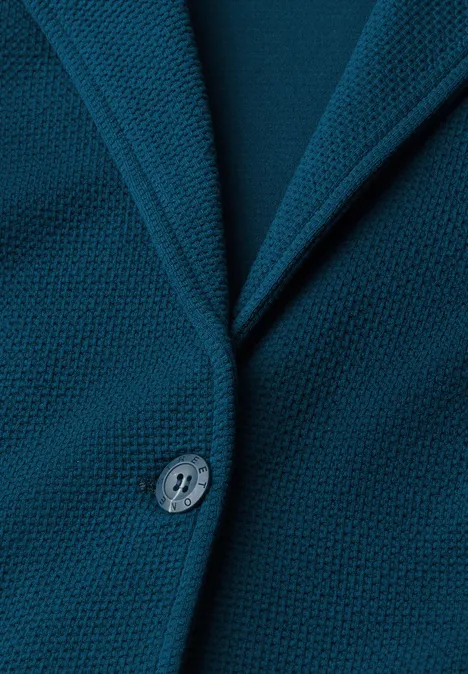 Nahaufnahme eines tealblauen Strickblazers mit Reverskragen und Knopf