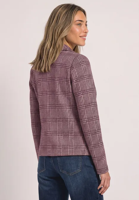 Vrouw in paarse geruite blazer, kijkt over haar schouder, stijlvol en casual.