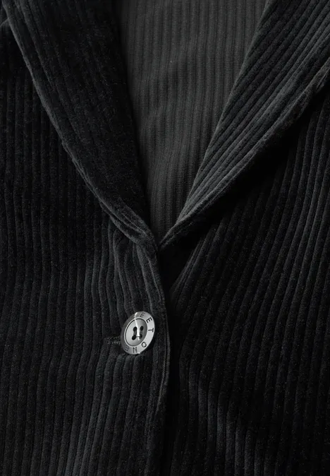 Gros plan d'un blazer en velours côtelé noir avec bouton et revers, texture à fines côtes visible.