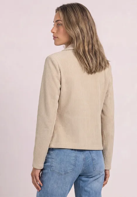 Femme de dos, veste beige clair et jean bleu.