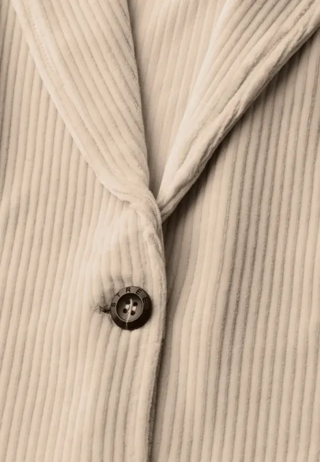 Gros plan d’un manteau en velours côtelé beige avec un bouton