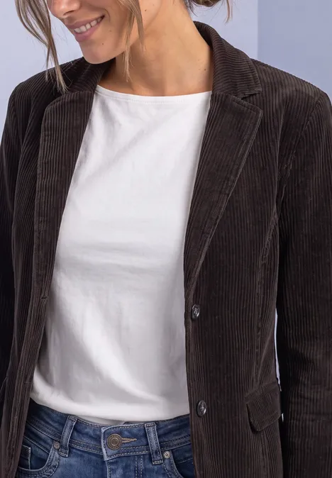 Personne porte un T-shirt blanc, un blazer en velours côtelé marron et un jean.