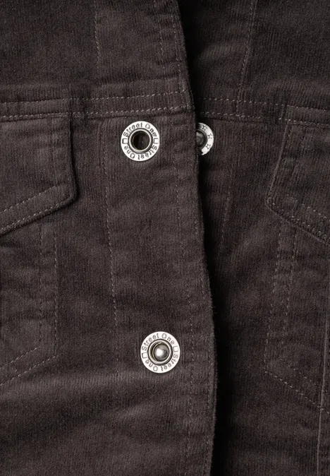 Close-up van een donkerbruine corduroy jas met glanzende zilverkleurige drukknoopsluiting.