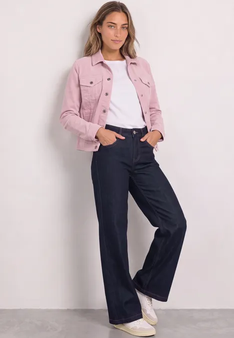 Jacke aus Cord mit Knopfleiste quiet rose Frau in rosa Jeansjacke, weißem Shirt und weiten dunklen Jeans, weiße Sneaker, vor hellem Hintergrund.