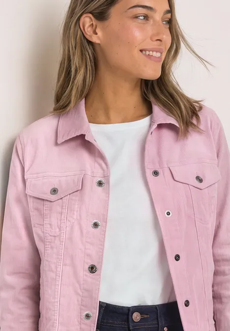 Jacke aus Cord mit Knopfleiste quiet rose Frau trägt rosa Jeansjacke über weißem T-Shirt und lächelt seitlich in die Kamera.