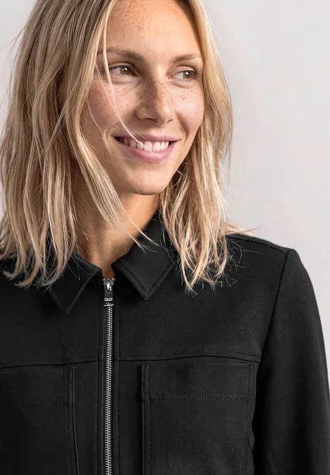 Jas met overhemdkraag en borstzakken Black Close-up van een glimlachende blonde vrouw in een zwarte jas, die naar rechts kijkt.
