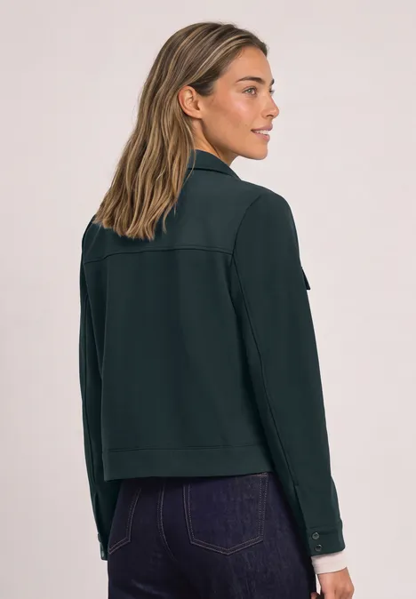 Jas met overhemdkraag en borstzakken stormy green Vrouw in donkergroene jas gezien van achter, kijkt over haar schouder, los haar.