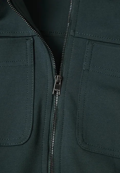 Jas met overhemdkraag en borstzakken stormy green Close-up van een donker kledingstuk met centrale ritssluiting en twee opgezette zakken.