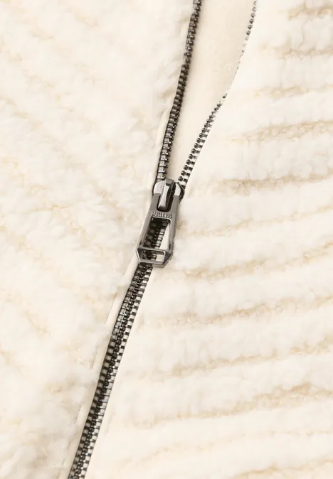 Teddy-Jacke mit Zick-Zack-Struktur pure beige Nahaufnahme eines cremefarbenen Fleece-Jackets mit sichtbarem Metallreißverschluss.