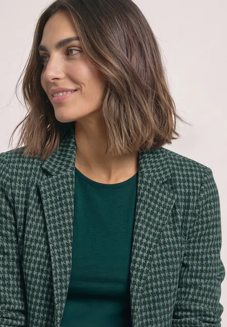 Basic Blazer mit Reverskragen und Muster stormy green Frau mit schulterlangem braunen Haar in grünem Shirt und Hahnentritt-Blazer, lächelnd seitlich blickend.