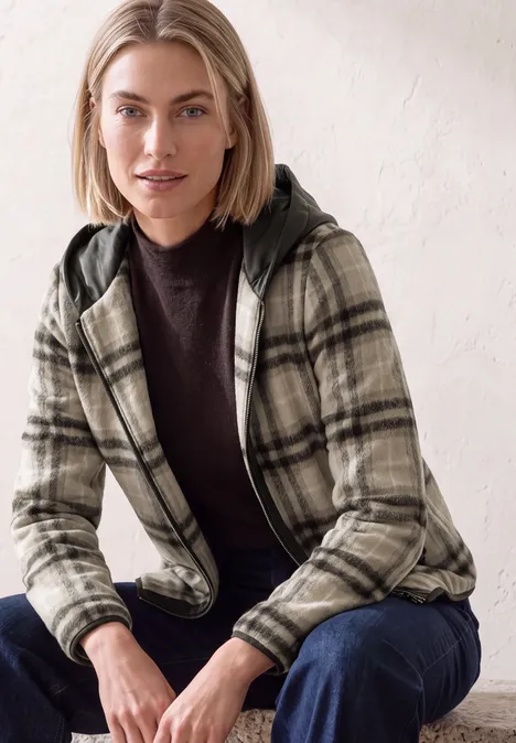 Jacke mit Wollanteil und Kapuze black coffee Eine Frau mit kurzem blondem Haar trägt eine karierten Kapuzenjacke und dunkles Oberteil und sitzt entspannt.