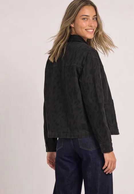 Jeansjacke mit Leo-Muster und Kragen Leo Print Washed Junge Frau mit schwarzer Jeansjacke blickt lächelnd über die Schulter.