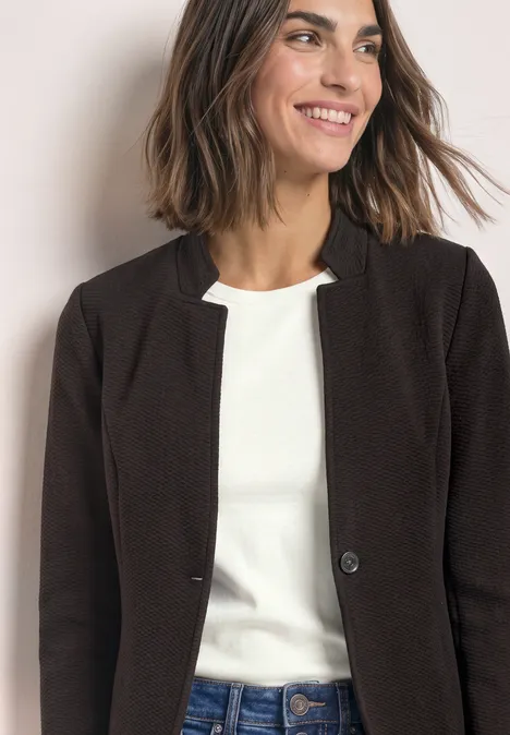 Blazer aus Jersey mit Struktur black coffee Frau lächelt, trägt weißes T-Shirt und dunkelbraune Blazerjacke, schaut seitlich.