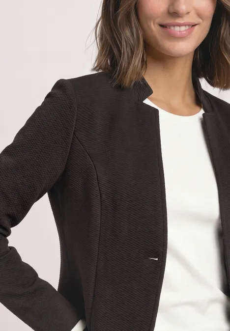Blazer aus Jersey mit Struktur black coffee Frau trägt dunkelbraunen Blazer über weißem Top, lächelt leicht.