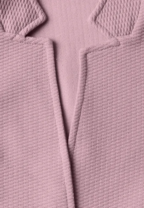 Nahaufnahme eines rosa strukturierten Stoffblazers mit sichtbarem Kragen und Revers.