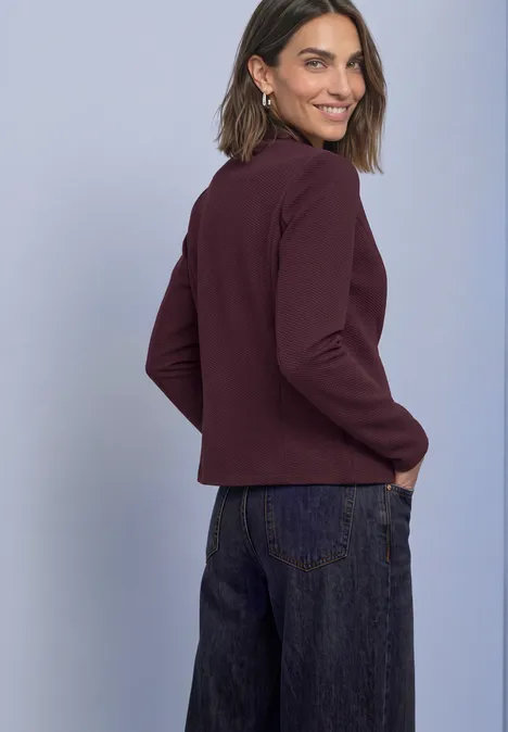 Blazer van jersey met structuur berry plum Vrouw in een bordeaux blazer en donkere jeans kijkt lachend over haar schouder.