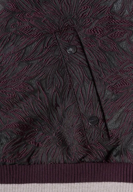 Dunkellila Jacke mit organischem, reliefartigem Muster, sichtbaren Knöpfen und geripptem Saum.
