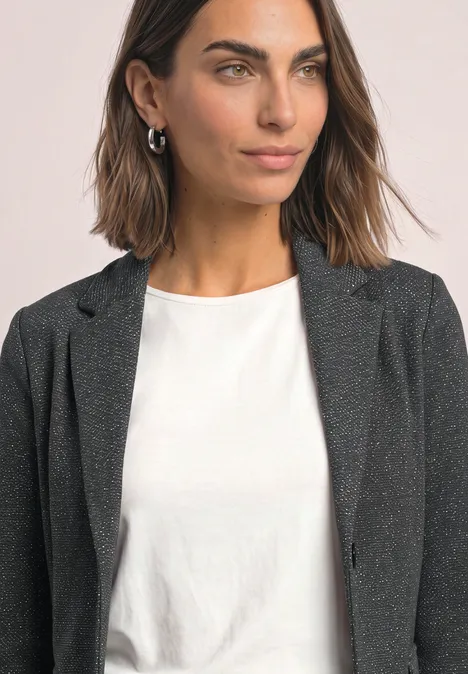 Portret van een vrouw met bruin haar, zwarte blazer en wit T-shirt.
